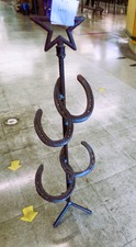 HORSE SHOES welded into a stand with star on top.  Not sure - umbrella stand?  cane holder?  fishing poles?  
$26.30